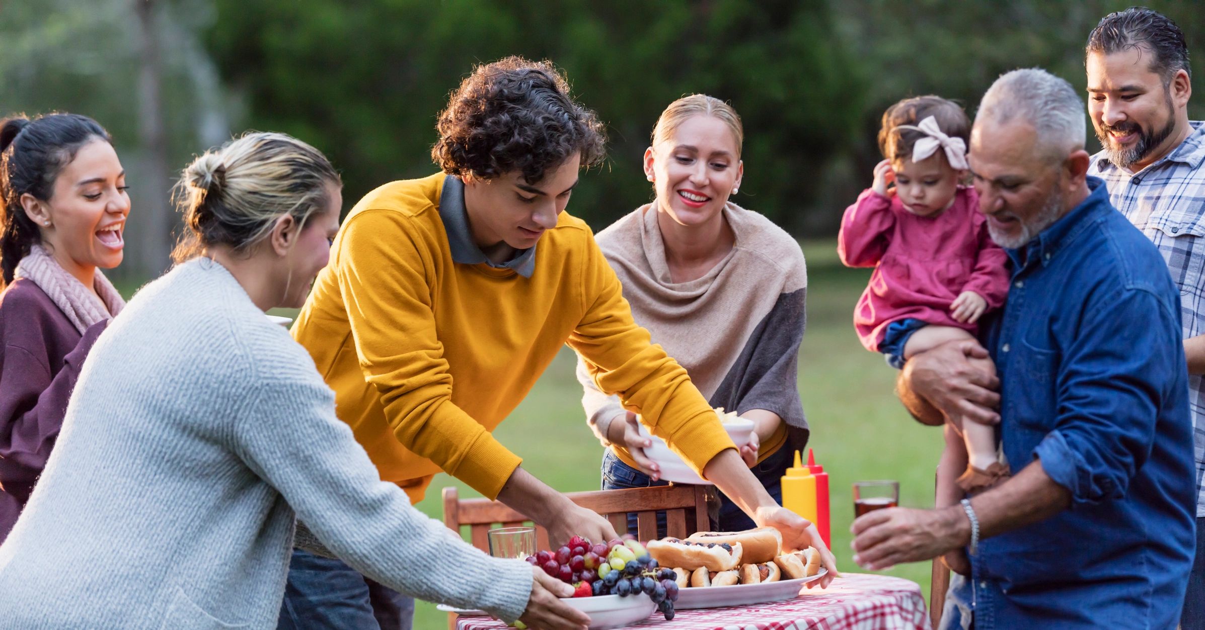 Multi-generation family smiling at a backyard picnic